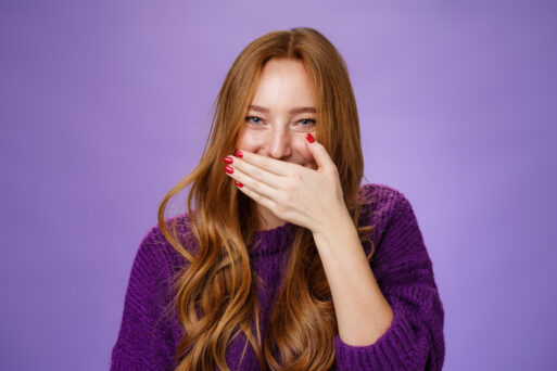 Close-up shot of girl having fun giggling, covering mouth with palm as holding laugh smiling sincere and carefree reacting to hilarious joke or prank posing over purple background.
икота
