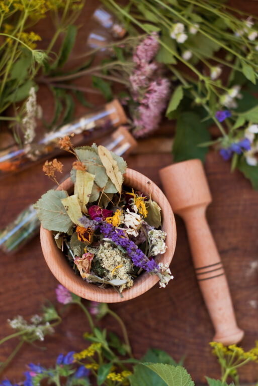 Homeopathy and herbal medicine concept. Wooden mortar and pestle with dry herbs, wildflowers, chalkboard and glass bottles on a wooden background
целебные растения травы