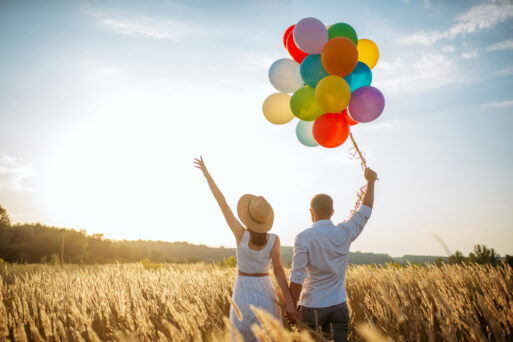 Love couple with balloons, leisure in a rye field on sunset. Pretty wife and husband walking on summer meadow
счастье