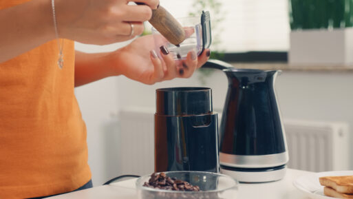 Using coffee grinder to make fresh coffee for breakfast. Housewife at home making fresh ground coffee in kitchen for breakfast, drinking, grinding coffee espresso before going to work
кофемолка