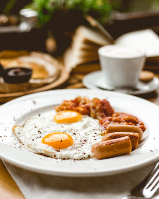 side view two fried eggs with sausages beans and bacon on a plate
Завтрак