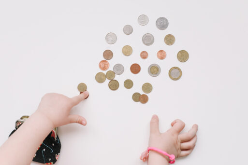 Toddler girl hands play with coins. Learning financial responsibility and planning savings concept
бросить монету