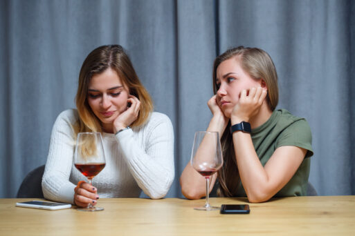 Two girls of European appearance are sitting at the table with glasses of wine. Conversation of girlfriends with alcoholic drinks.
Зависть к подруге