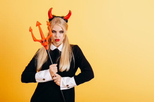 devil woman standing against a yellow background with menacing look. - Vertical image
дурная примета