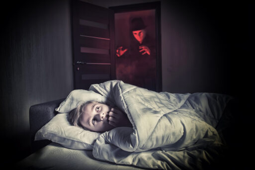 Nightmare. Scared boy lying in the bed while the masked stranger standing in a doorway
ночной кошмар